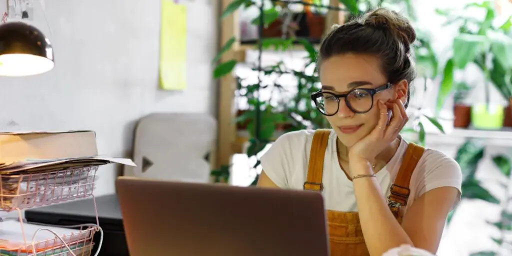 Woman sitting at her laptop resting her head on her hand.