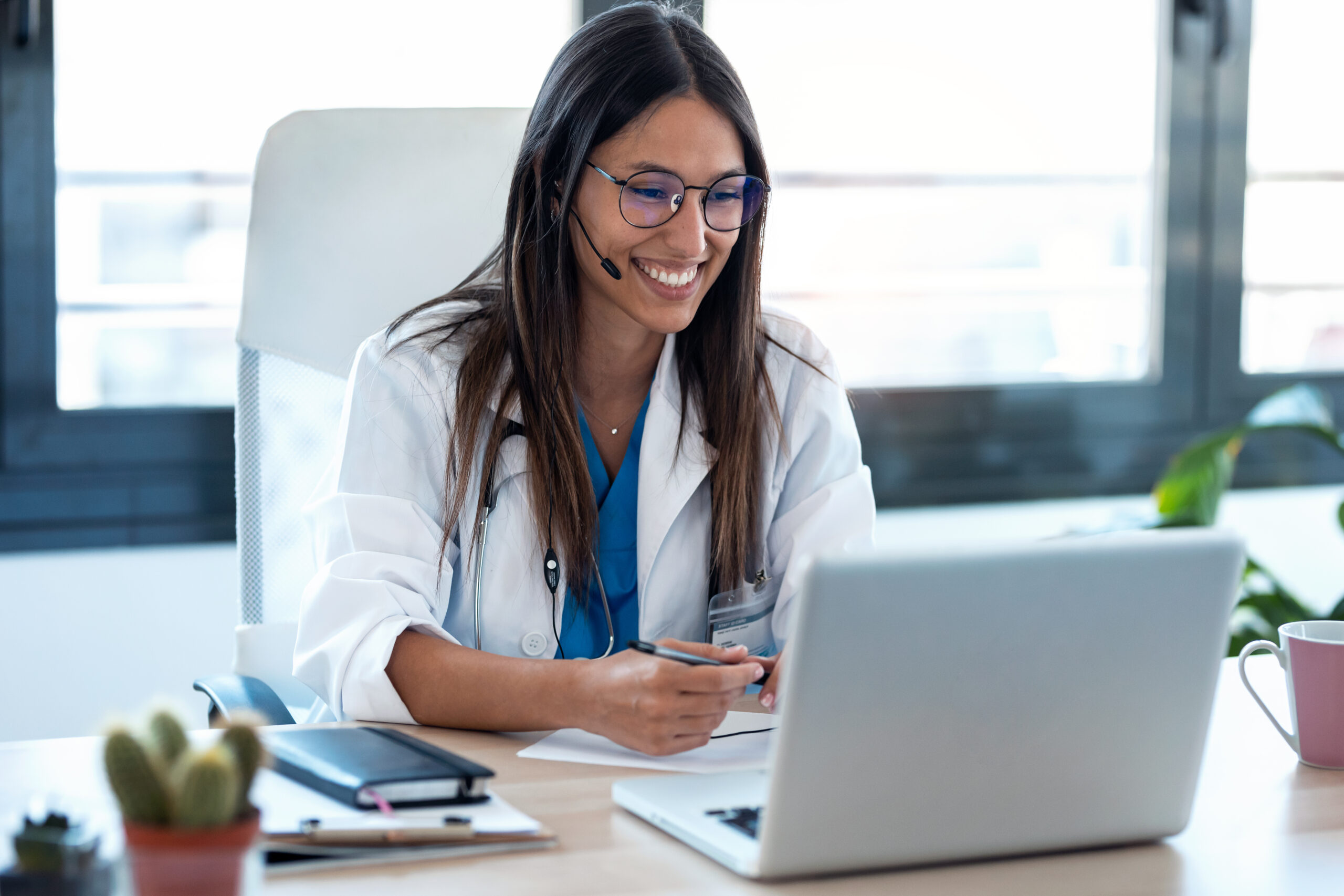 Smiling physician sitting in front of a laptop
