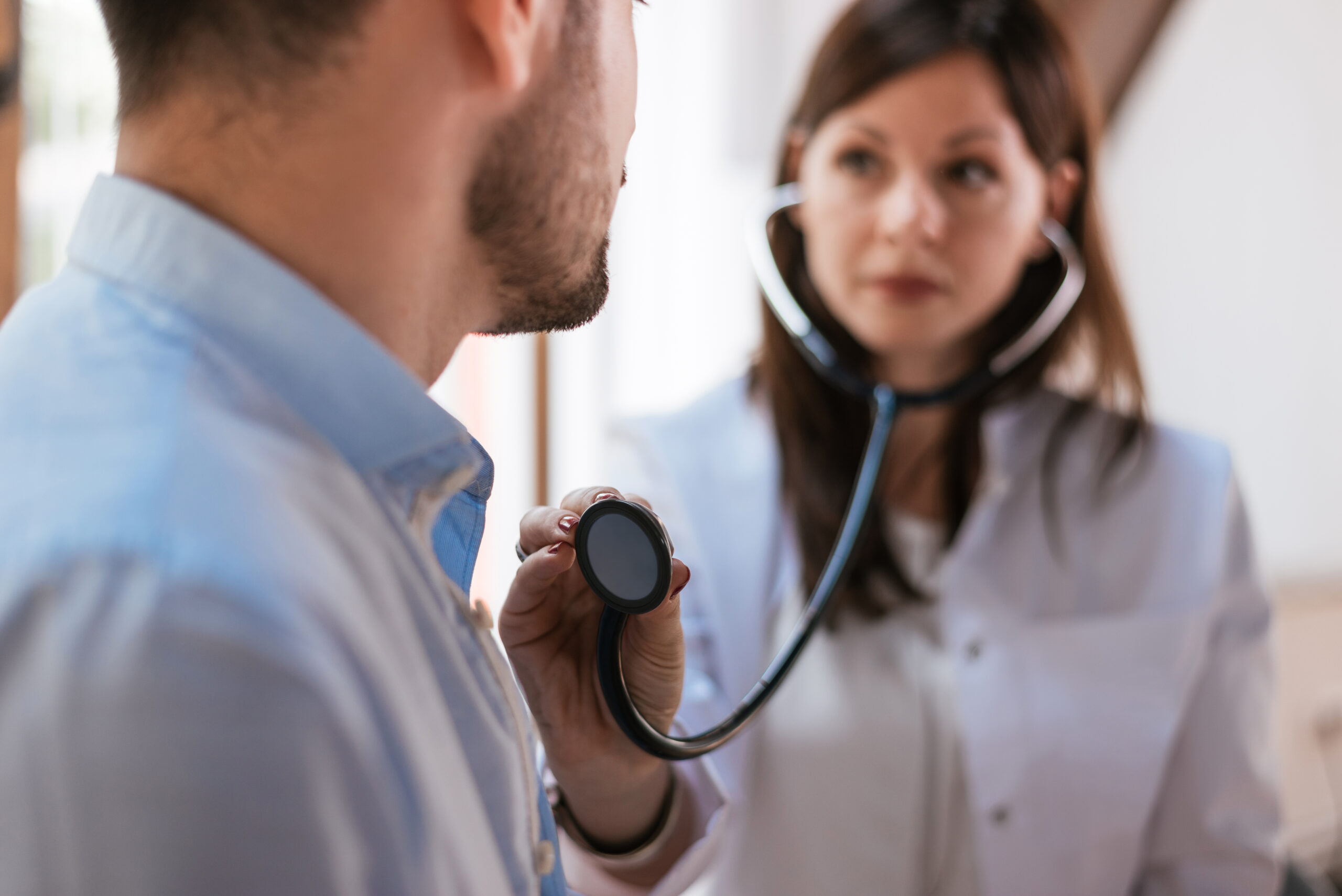 Physician using stethoscope on patient to examine the heart function