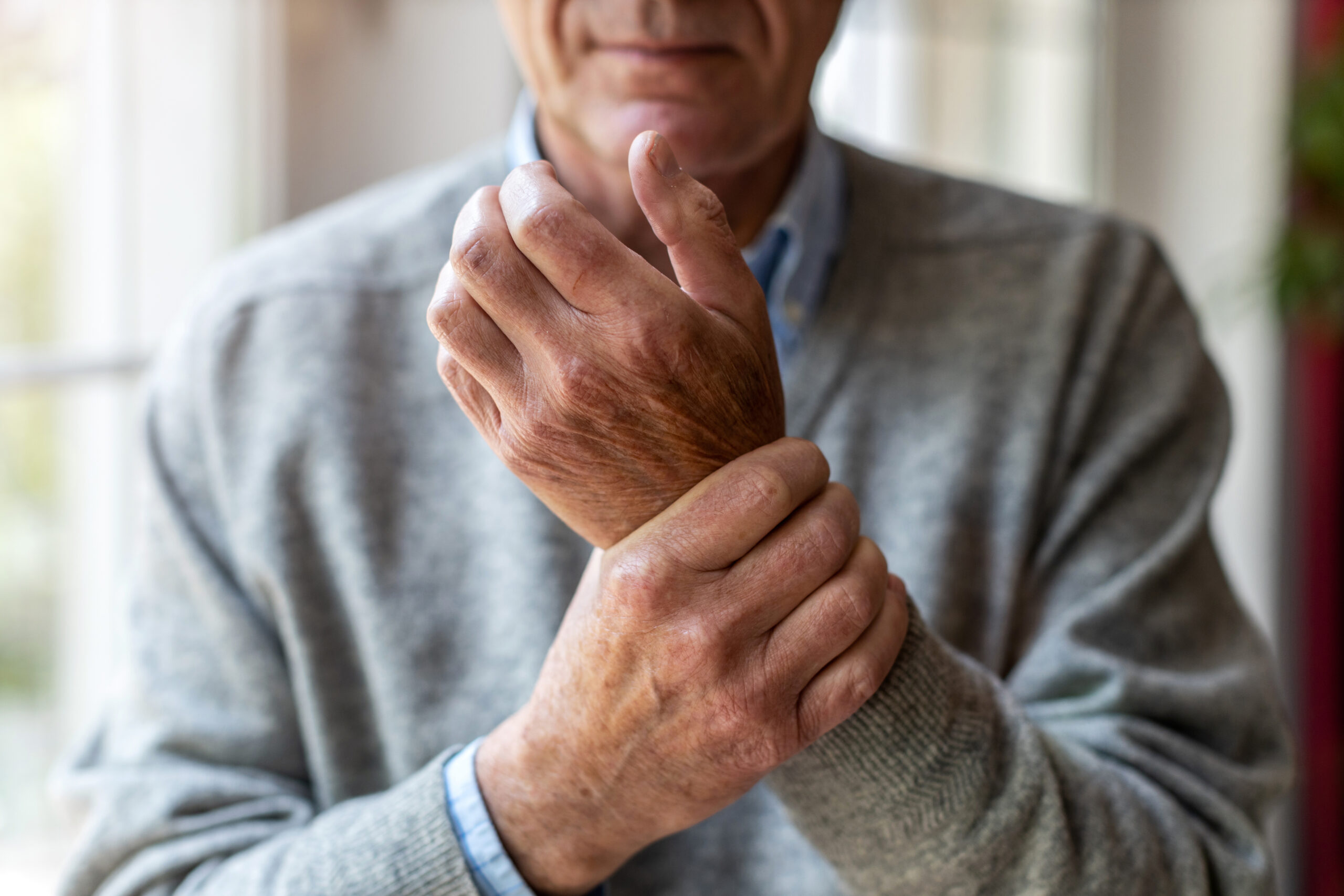 An elderly Sjögren's syndrome patient holds his wrist