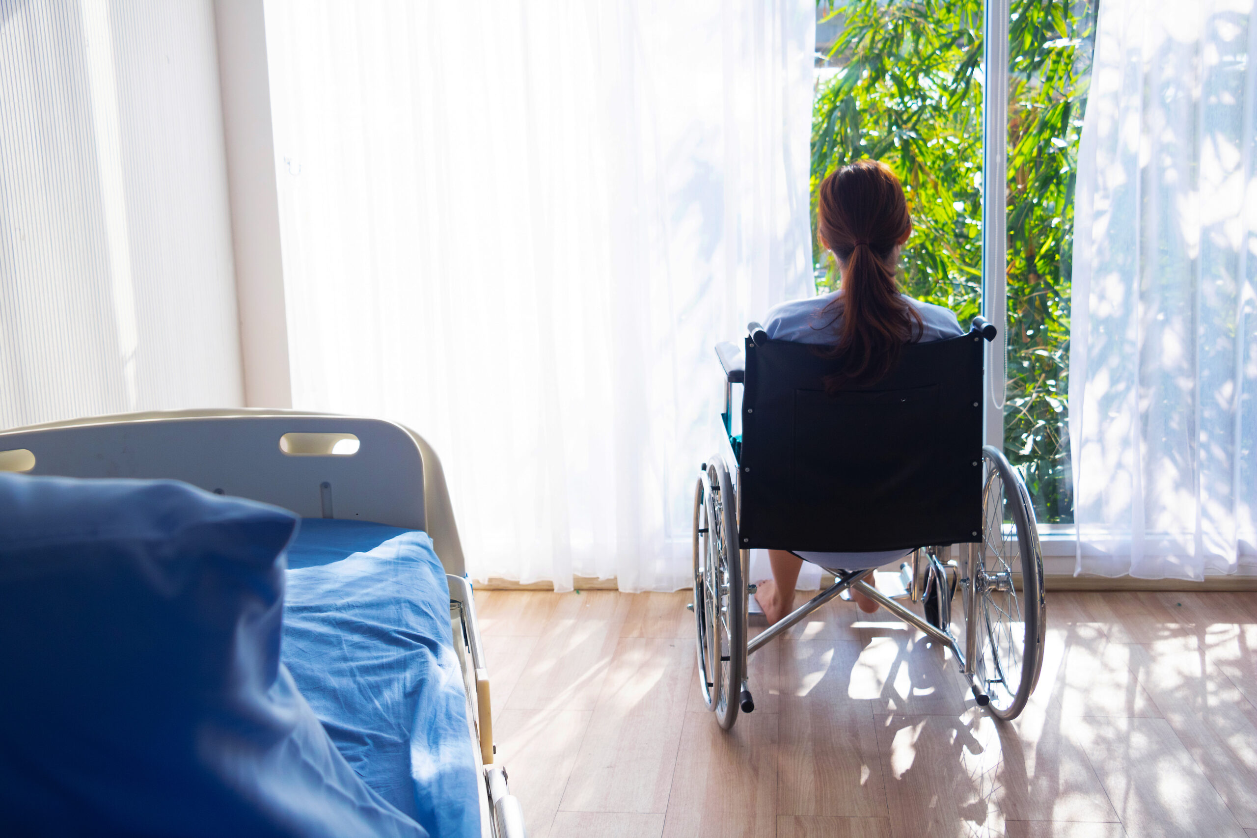 Multiple sclerosis patient in wheelchair looking outside the window