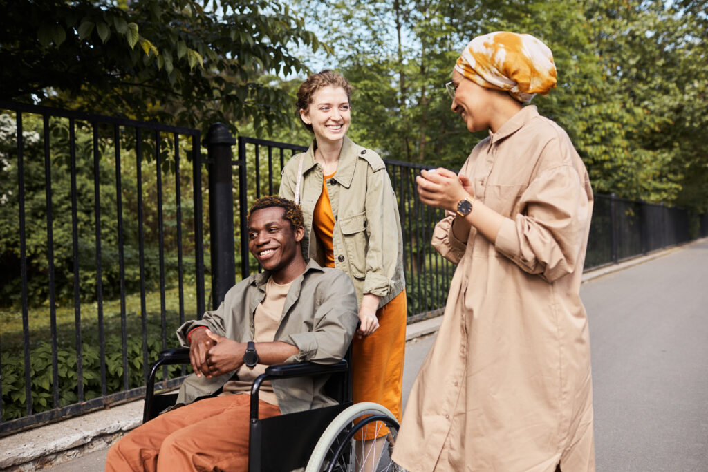 Three friends spending time together, one pushing another in a wheelchair