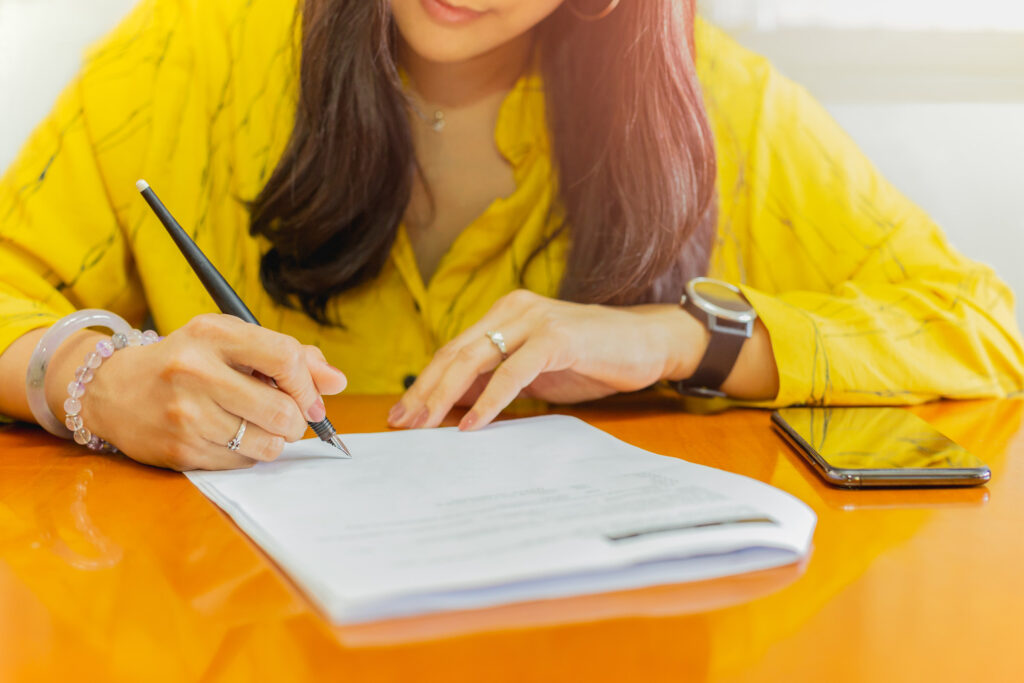 Woman writing on paper at a table, learning about clinical trials