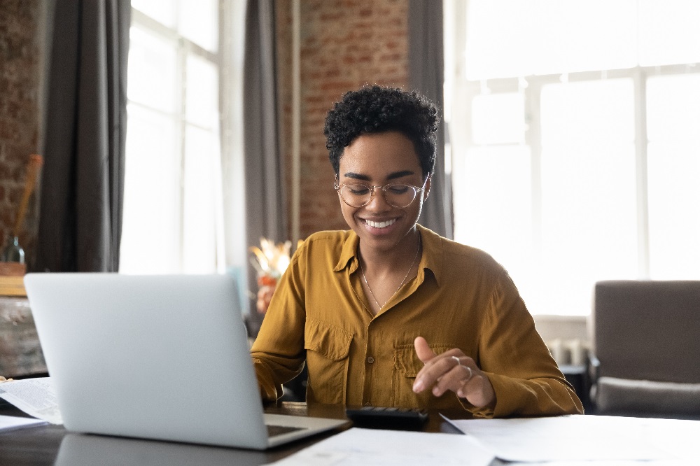 A woman sat at a laptop smiling.